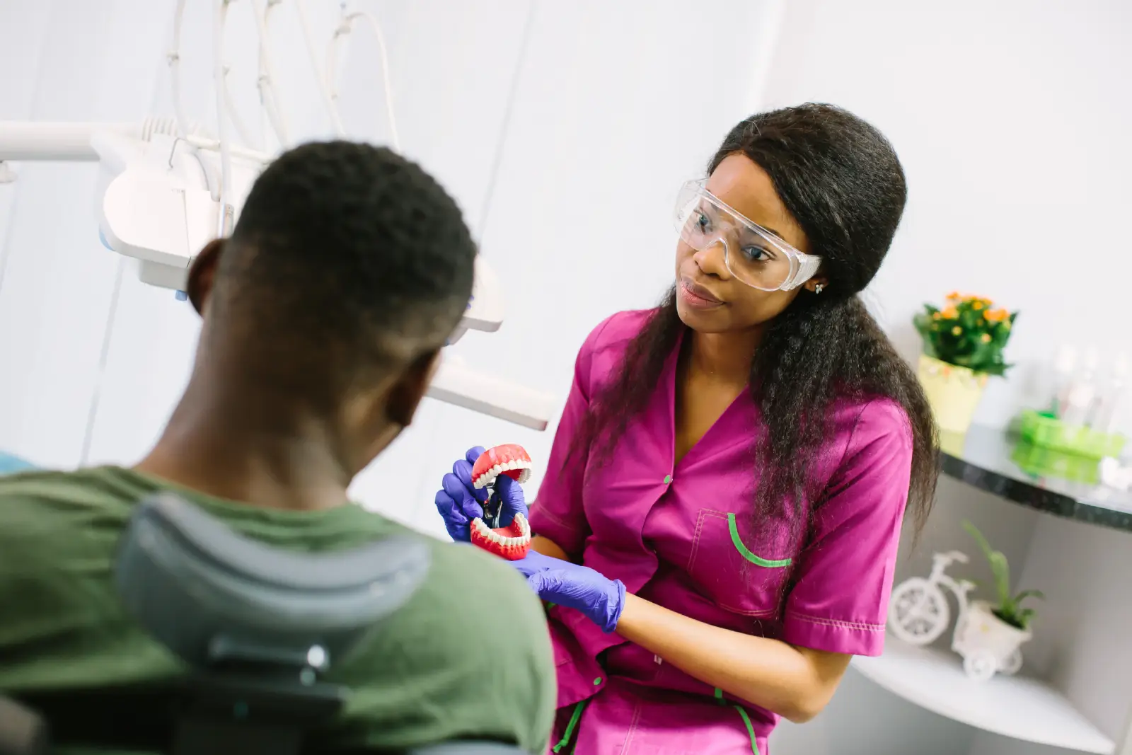 friendly female emergency dentists in mansfield showing teeth model to his patient