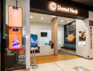 Dental clinic entrance with signage, seating area, and promotional displays.