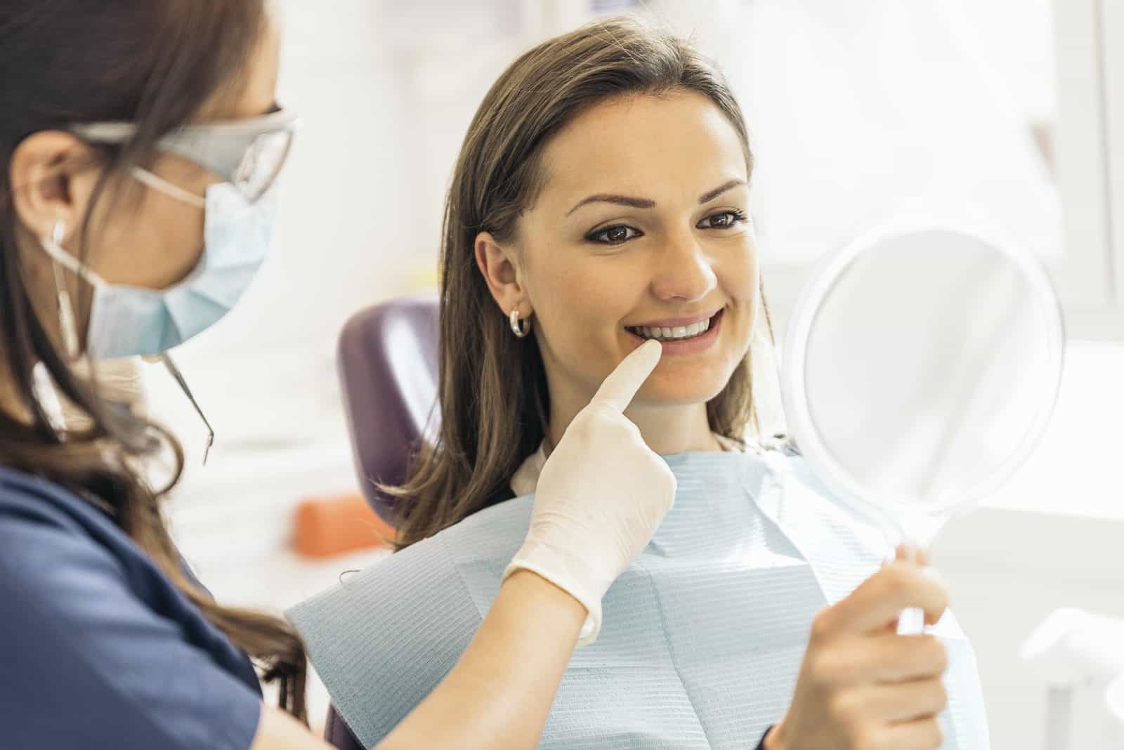 Patient admiring her smile in a mirror after cosmetic dentistry at Dental Nook Brisbane
